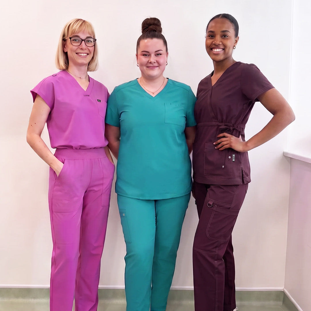 Three women standing and posing for a picture wearing scrubs