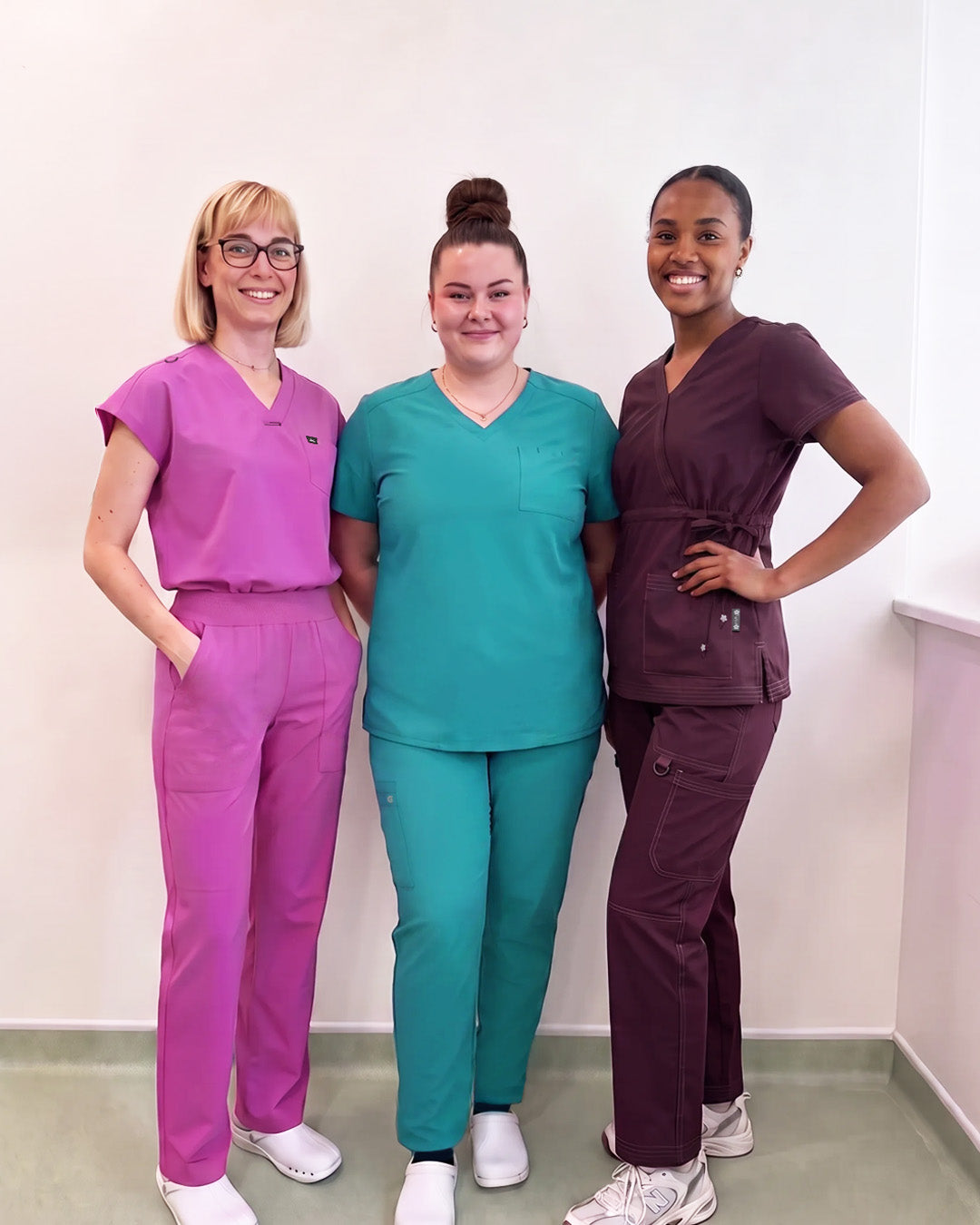 Three women standing and posing for a picture wearing scrubs